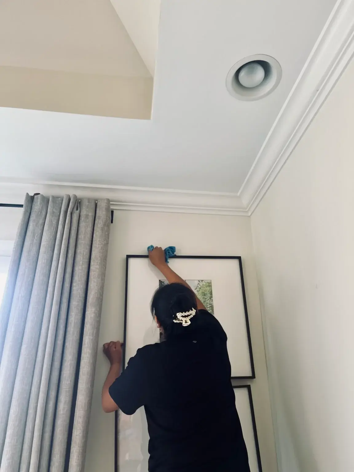 Cleaner dusting a framed picture during a deep clean